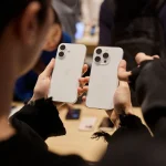 Seorang pembeli membandingkan iphone standard dan pro